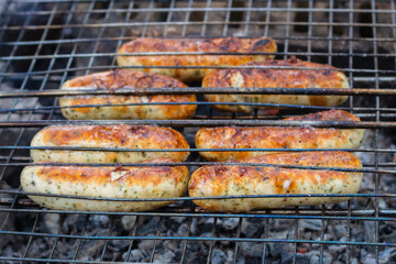 Grilled sausages on the grill. Barbecue meat. Roasted kebab. Grilled food. Smoked sausages outdoor. Fried cuisine. Camping concept. Delicious BBQ bratwurst. Idyllic picnic concept. Bonfire with grill.