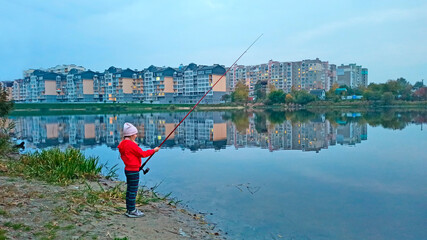 girl fishing on river overlooking large residential area. City landscape