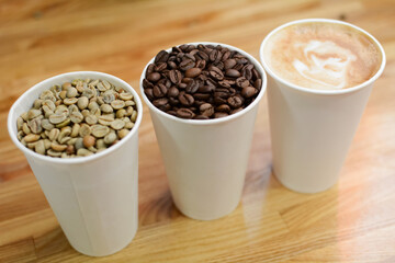 three cardboard cups with coffee beans and cappuccino coffee