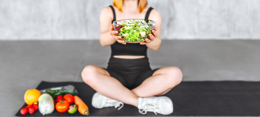 A sporty woman in sportswear is sitting on the floor with healthy food.