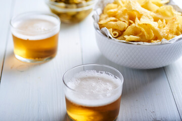 white wooden table with glasses of beer and a bowl full of potatoes