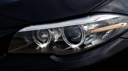 Fototapeta na wymiar Headlights of black modern car close up.