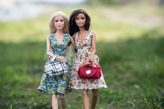Mulhouse - France - 11 April 2021 - Portrait of blond and brunette barbie dolls wearing summer dresses walking in border river