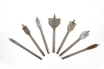 Metal feather drills of various diameters arranged in a fan isolated on a white background, a joiner's construction tool.