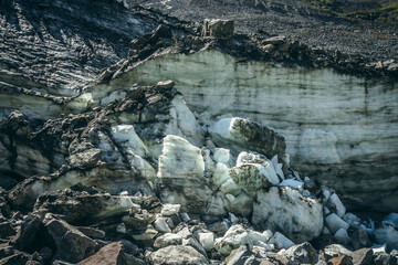 Nature background with icefall near glacier wall with cracks and scratches. Natural backdrop with icy wall and blocks of ice. Beautiful landscape with shiny glacial wall and ice blocks in sunlight.