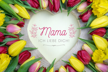 Mama ich liebe dich. Herz aus Holz umgeben von Blumen (Tulpen) mit Glückwunsch zum Muttertag.