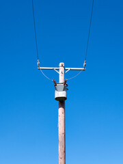Obraz premium An electricity supply pylon delivering power through the UK national grid showing power cables, isolators and other equipment. Taken on a sunny day with a blue sky.