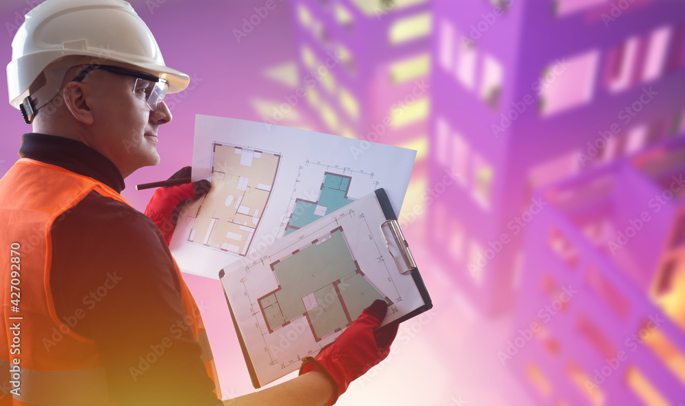 Poster builder with blueprints drawings in hand. he smiles as he looks at architectural drawings. concept c