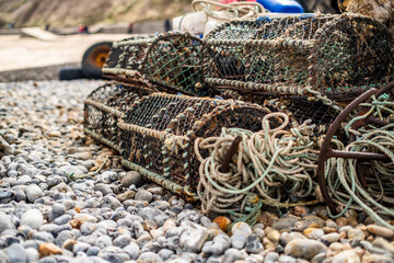 Crab fishing gear left on Cromer beach comprising fishing pots, rope, metal anchor and fenders. Shallow depth of field, selective focus and bokeh