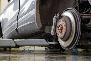 A modern car on a lift in a car service with a wheel removed. Brake disc, brake caliper. Car service and spare parts.