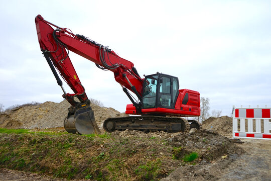 Roter Bagger und eine Baustellenbake auf einer sandigen Baustelle, Tiefbau, Erdbau, Stra&szlig;enbau, Kanalbau, Erschlie&szlig;ung