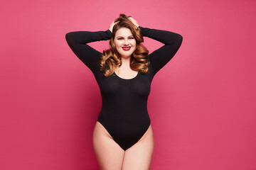 A young plus-size model woman with bright makeup and full red lips wearing a black bodysuit...