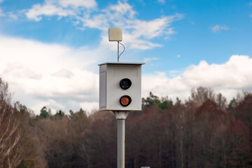 Speed camera for measuring speed of passing vehicles stands at countryside road.