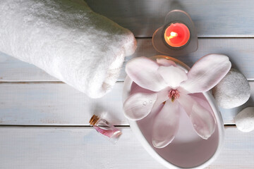 beautiful pink magnolia flower, smooth white stones in a stack, candles, white towel, concept of...