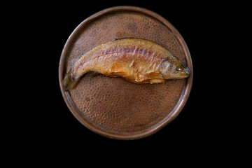closeup fried river fish rainbow trout, Oncorhynchus mykiss lies on a copper platter, traditional food preparation concept, food rich in phosphorus
