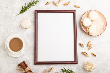 Brown wooden frame mockup with cup of coffee, almonds and macaroons on gray concrete background. top view