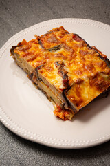 Eggplant parmigiana traditional Italian dish: baked eggplant. Baked eggplant with eggplant, cheese, tomatoes and spices on a white plate.