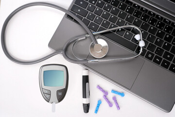 medical stethoscope, diabetic lancet set with spare needles, glucometer, laptop keyboard on white...