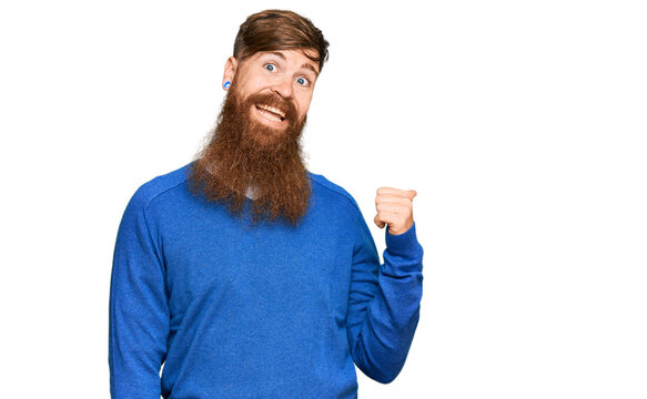 Young irish redhead man wearing casual clothes smiling with happy face looking and pointing to the side with thumb up.
