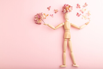 Wooden mannequin holding hydrangea flowers on pink pastel background. copy space.
