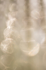 Abstract, bright and sparkling bokeh background. Golden, beige, silver and white. Blurred lighting from the glitter texture. Luxury design for overlay on presentation, mockup, posters. De-focused.