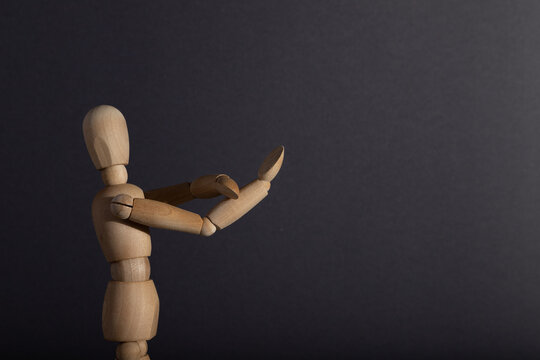 Wooden mannequin shows obscene gesture fuck off with hands on gray background. protest, riot, agression concept. copy space.