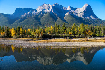 Fototapeta na wymiar River reflection with mountains and colourful autumn trees on sunny blue sky day 