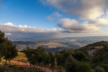 Aerial view of the Montserrat mountains on a beautiful spring day, Catalonia, Spain. Dramatic sky over the mountains. Sunlight falls through the clouds on the ground and mountains.