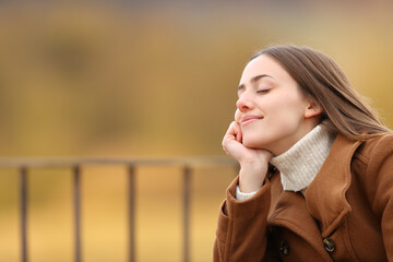 Woman relaxing with closed eyes in a balcony in winter