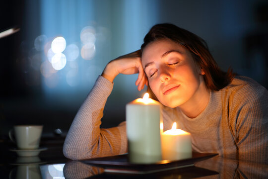 Relaxed woman smelling aromatic candles in the night