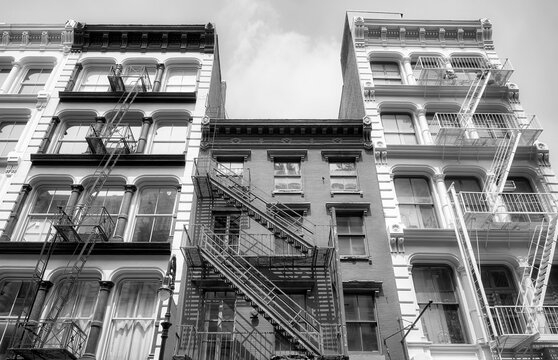 Black and white picture of old buildings with iron fire escapes, New York City, USA.