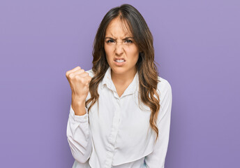 Young brunette woman wearing casual clothes angry and mad raising fist frustrated and furious while shouting with anger. rage and aggressive concept.