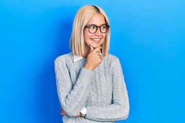 Beautiful blonde woman wearing glasses with hand on chin thinking about question, pensive expression. smiling with thoughtful face. doubt concept.