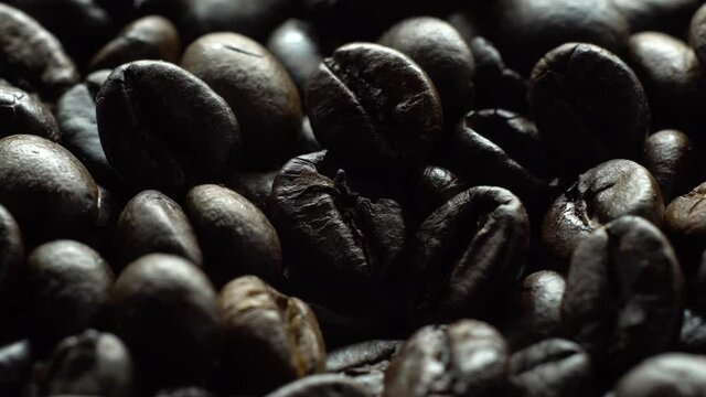 Coffee beans in rotation. Mixed Robusta and Arabica roasted Coffee beans. Coffee background. Coffee backdrop. Close up.
