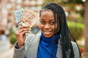 Young african american businesswoman smiling happy holding canadian dollars at the park.
