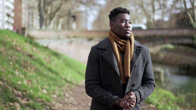 Young black man walking outside in nature during winter season