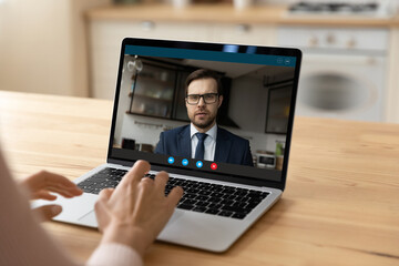 Confident young businessman in glasses on pc screen consult support female client by video call. Millennial male manager working from home office has remote meeting with customer using conference app