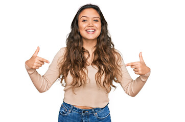Young hispanic girl wearing casual clothes looking confident with smile on face, pointing oneself with fingers proud and happy.