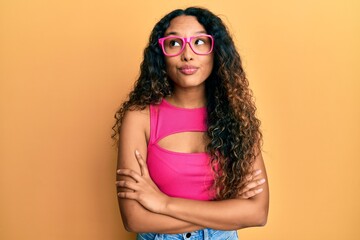 Young latin woman wearing casual clothes and glasses smiling looking to the side and staring away thinking.