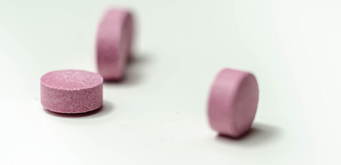 Purple pills scattered on a white background, food supplements which includes acai berries