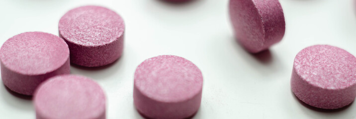Obraz na płótnie Canvas Purple pills scattered on a white background, food supplements which includes acai berries