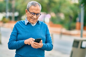 Senior grey-haired man smiling happy using smartphone at the city.