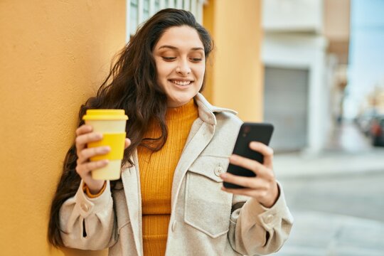 Young middle east woman using smartphone drinking coffee at the city.