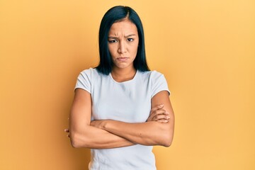 Beautiful hispanic woman wearing casual white tshirt skeptic and nervous, disapproving expression...