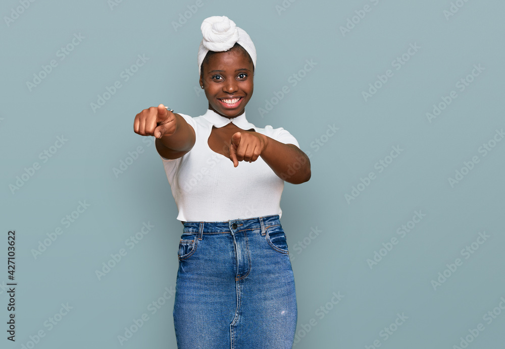 Poster Young african woman with turban wearing hair turban over isolated background pointing to you and the camera with fingers, smiling positive and cheerful