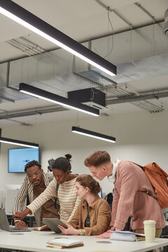 Vertical Shot Of Diverse Group Of Students Working Together And Using Digital Tablet While Standing At Table In School IT Lab, Copy Space