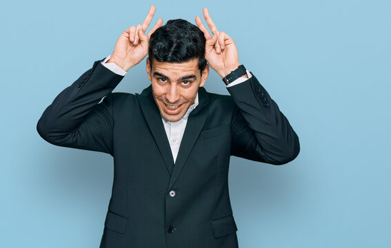 Handsome hispanic man wearing business clothes posing funny and crazy with fingers on head as bunny ears, smiling cheerful