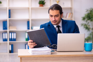 Chained male employee unhappy with excessive work in the ofiice