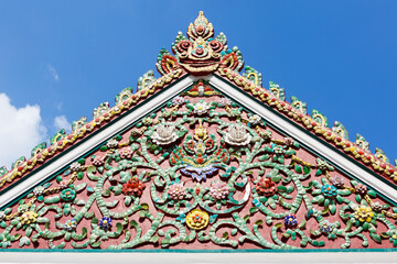 Beautiful pediment of a Buddhist temple decorated with ceramic mosaics depicting flowers