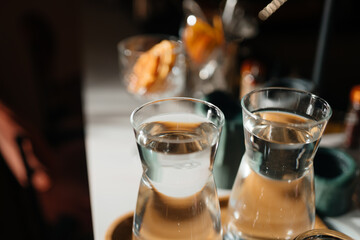 Four glass cups on the bar counter with serving accessories.